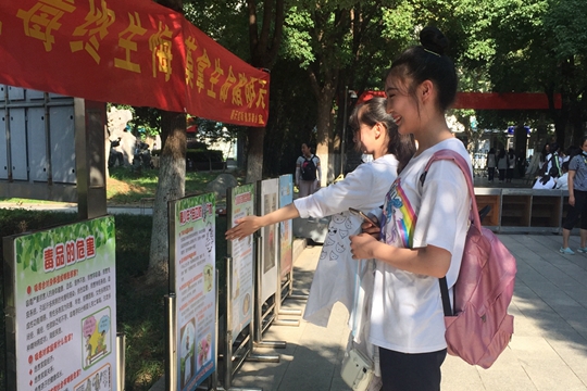 学生在“珍爱生命，远离毒品”和“暑期安全”专项教育展板前驻足观看